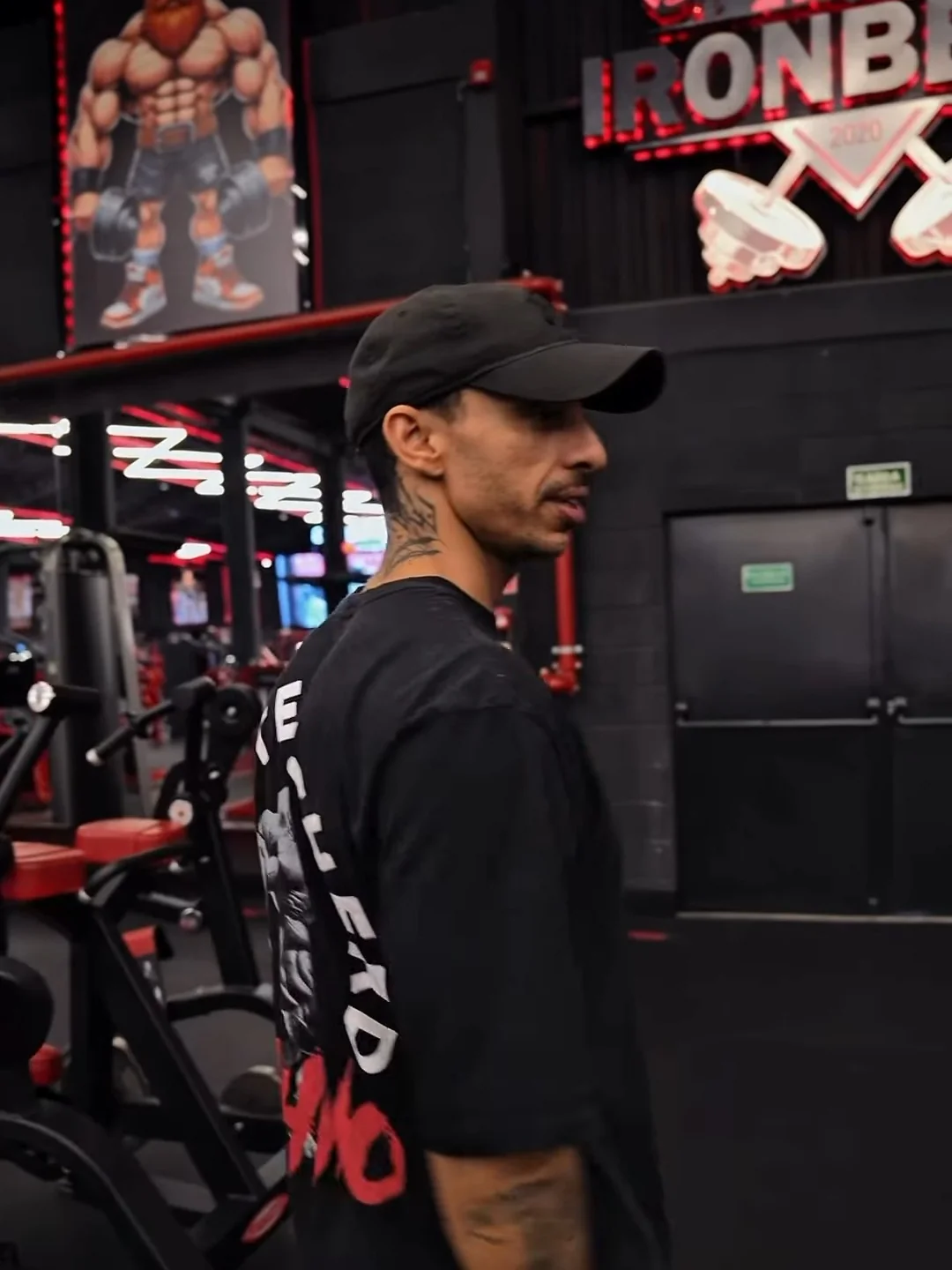 Kainã Soares de perfil, de boné, com a estampa RHINO nas costas da camiseta